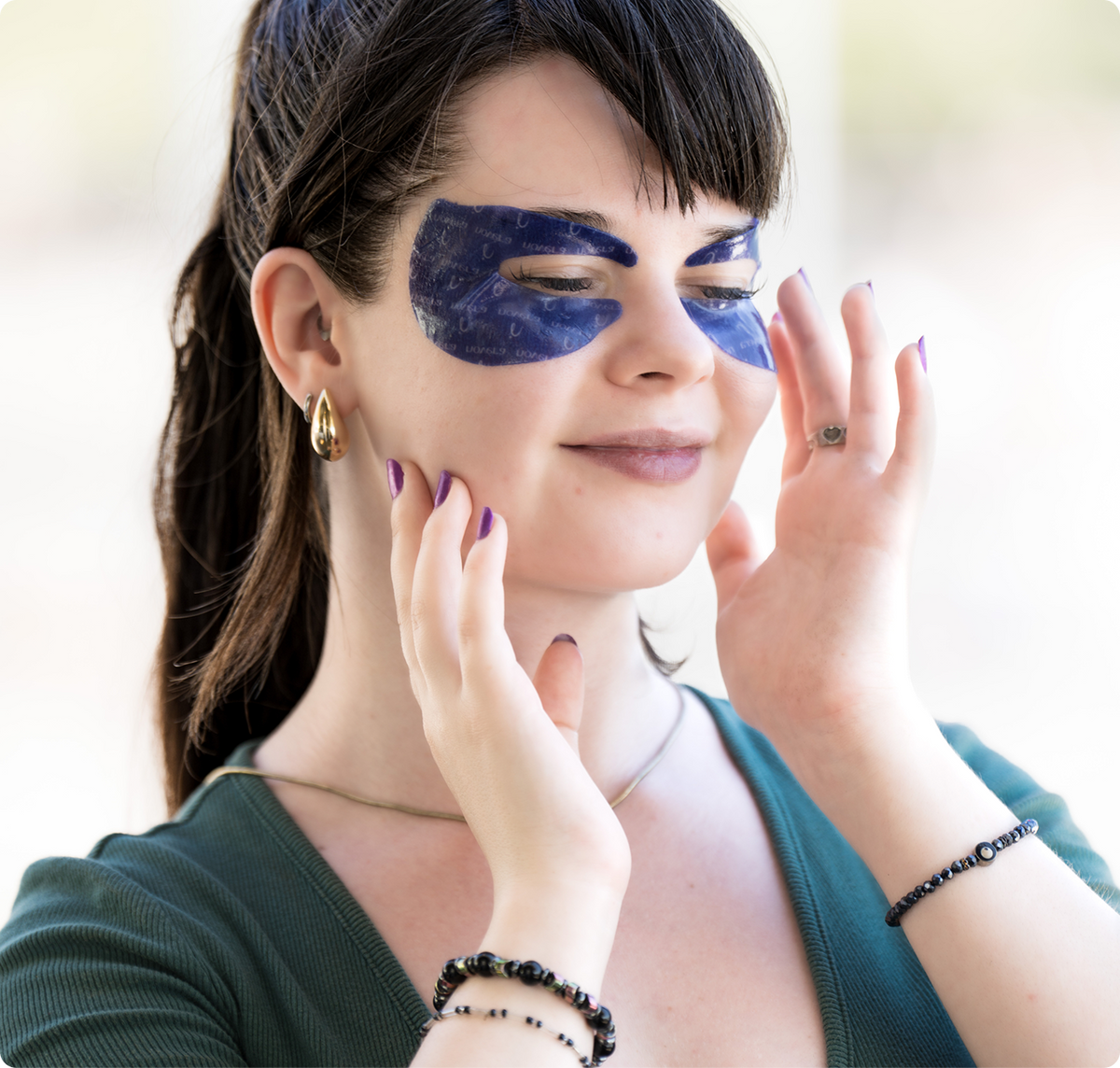 Woman pressing purple Lyrome hydrogel eye patches into place around her eyes