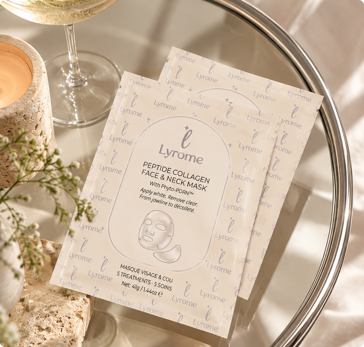 Two Lyrome Face and Neck Mask sachets arranged on a tray beside a glass
